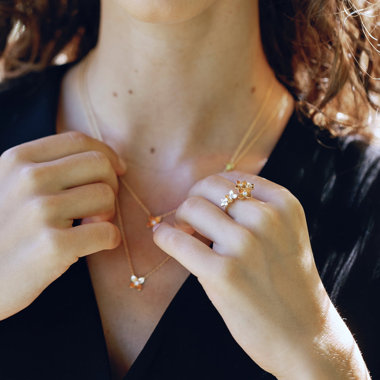 Close-up of a person wearing a delicate gold necklace with floral pendants.