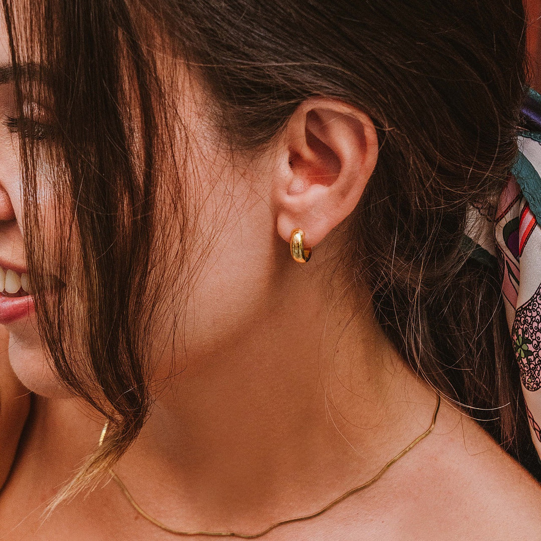 Close-up of mini huggie hoop earrings displaying small comfortable fit