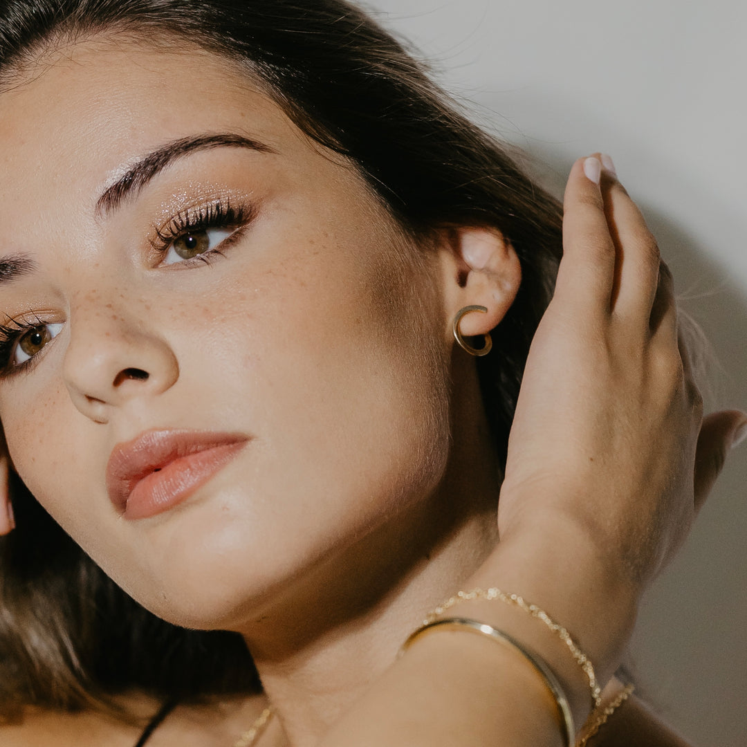 Sleek open hoop earrings in gold vermeil worn on ear showing twisted design