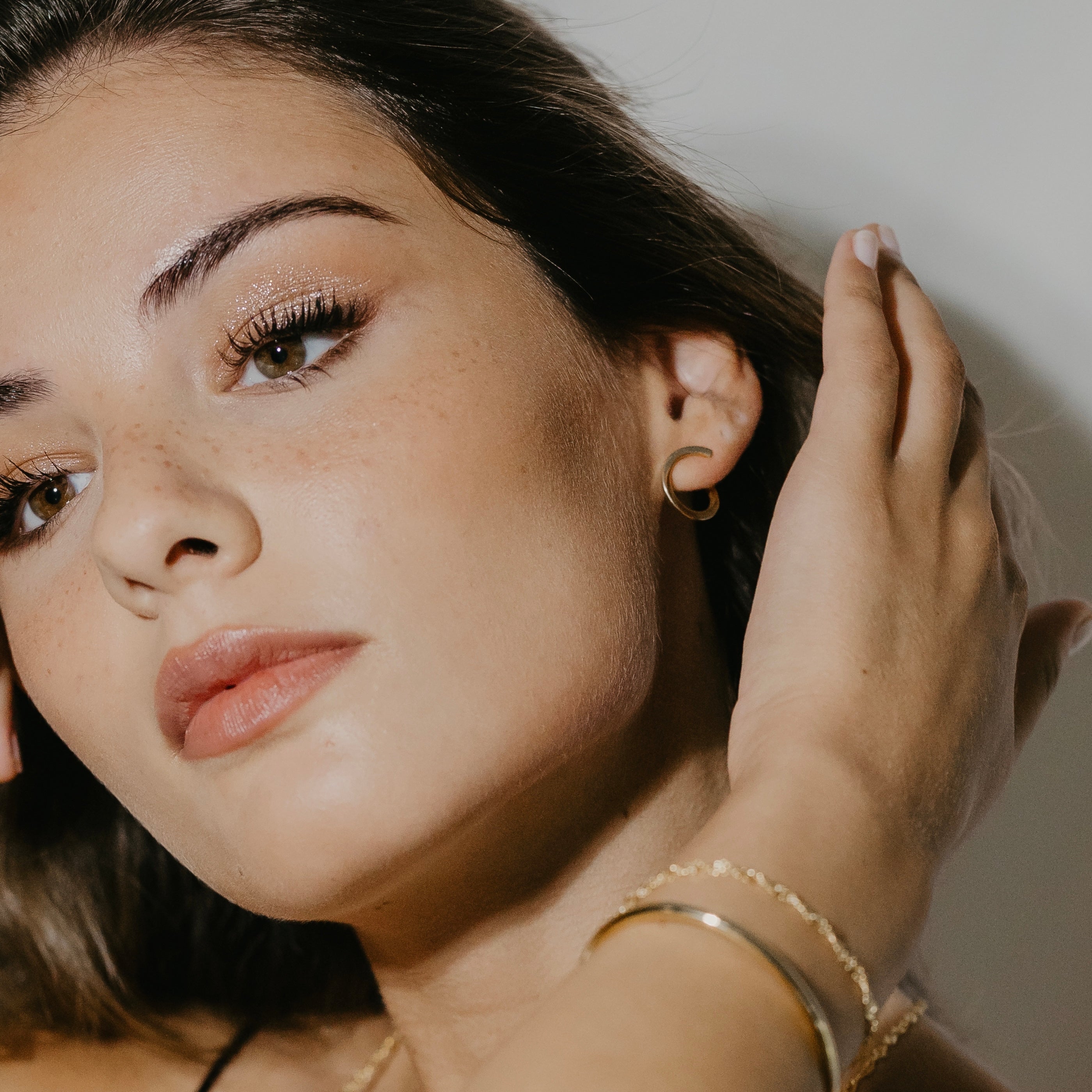 Sleek open hoop earrings in gold vermeil worn on ear showing twisted design