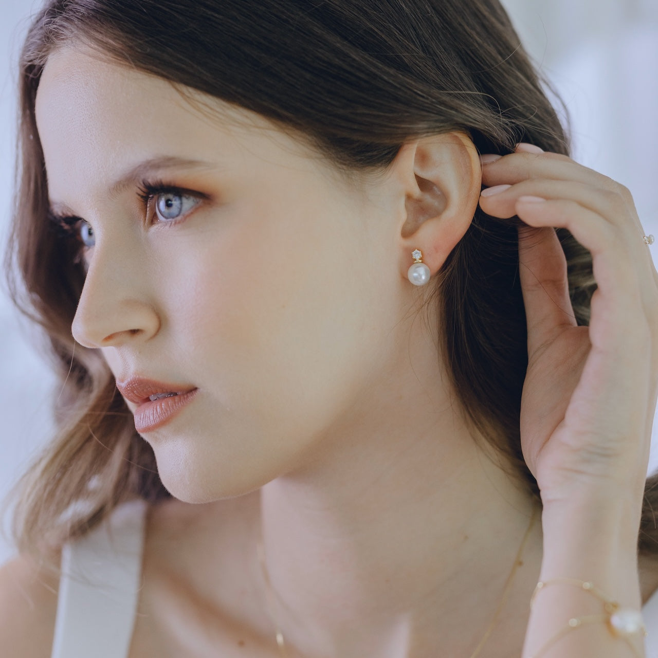 White topaz and pearl stud earrings in gold vermeil worn on ear
