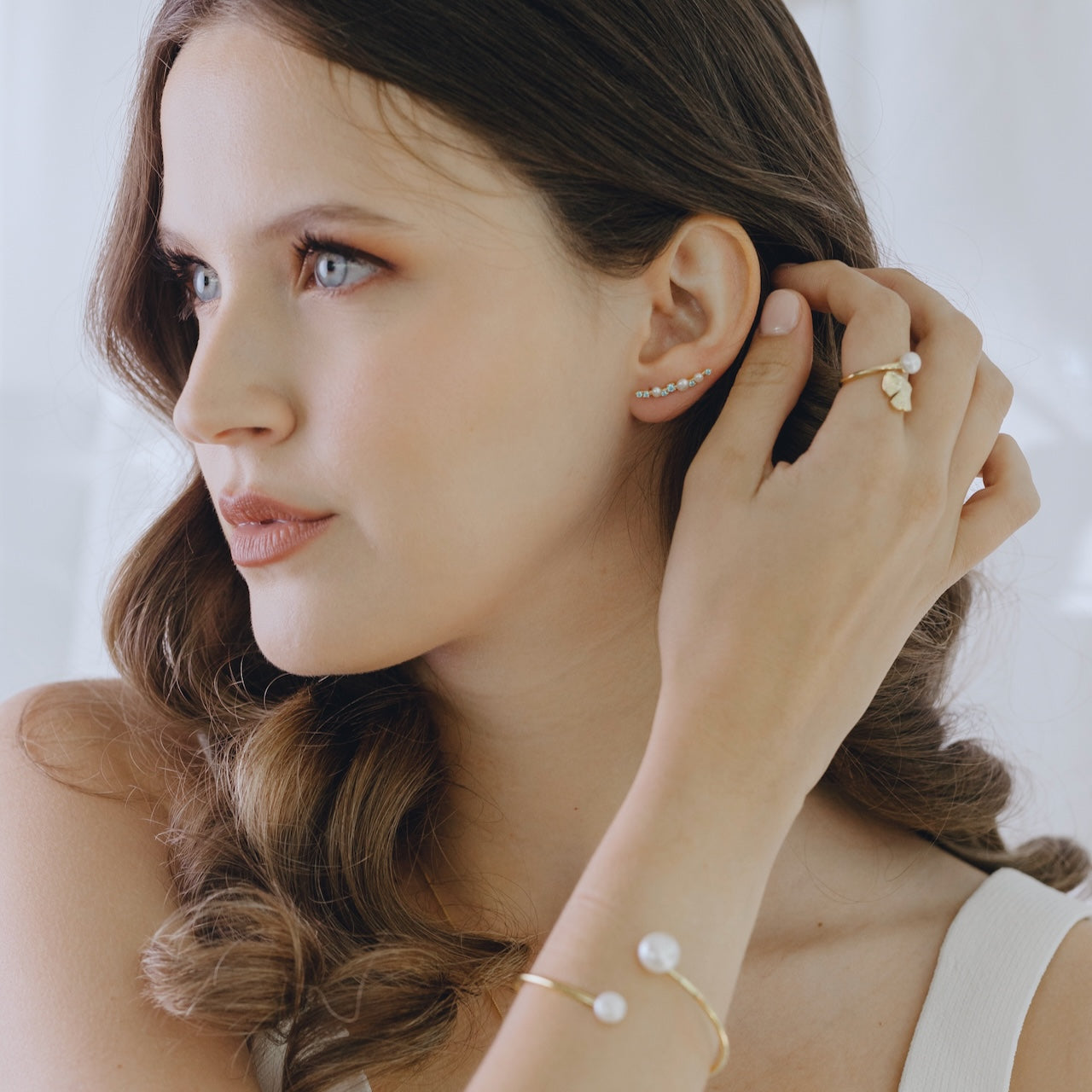 Pearl Obsession ear climbers with blue topaz styled on ear displaying climbing effect