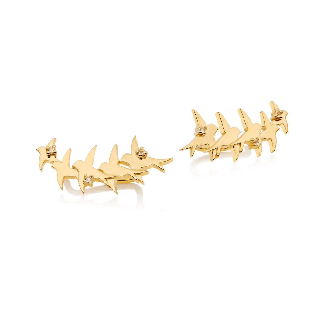 A pair of 18K gold vermeil ear climbers designed to resemble swallows in flight, displayed against a white background.