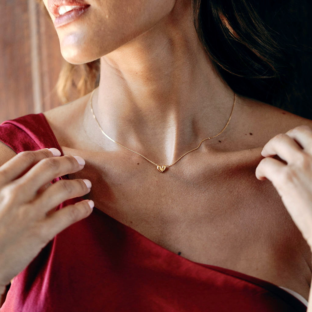 Gold vermeil heart shaped pendant necklace in model wearing a red dress