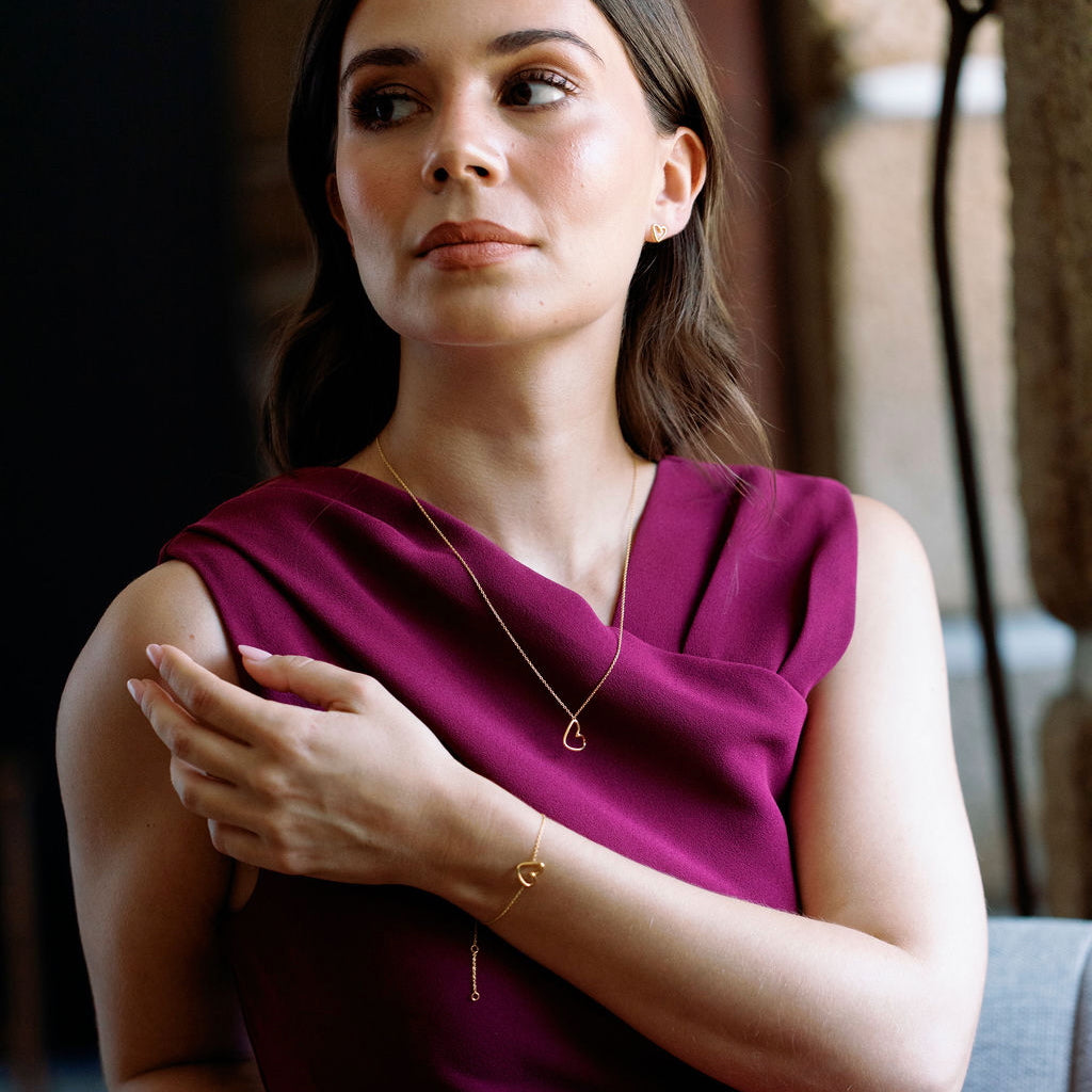 Woman wearing a purple dress with heart shaped jewellery with a blurred background