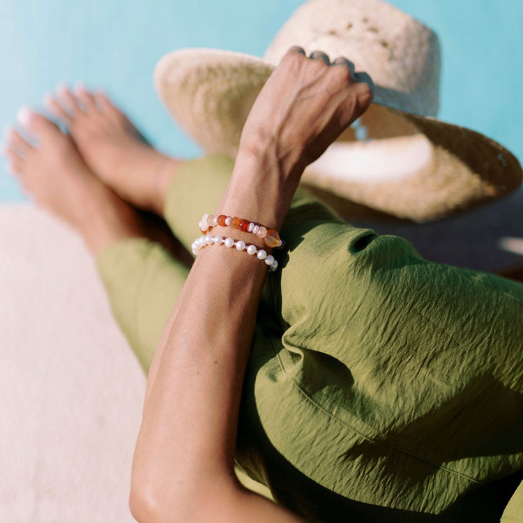 Person wearing a Morena bracelet with green dress on a turquoise blue background