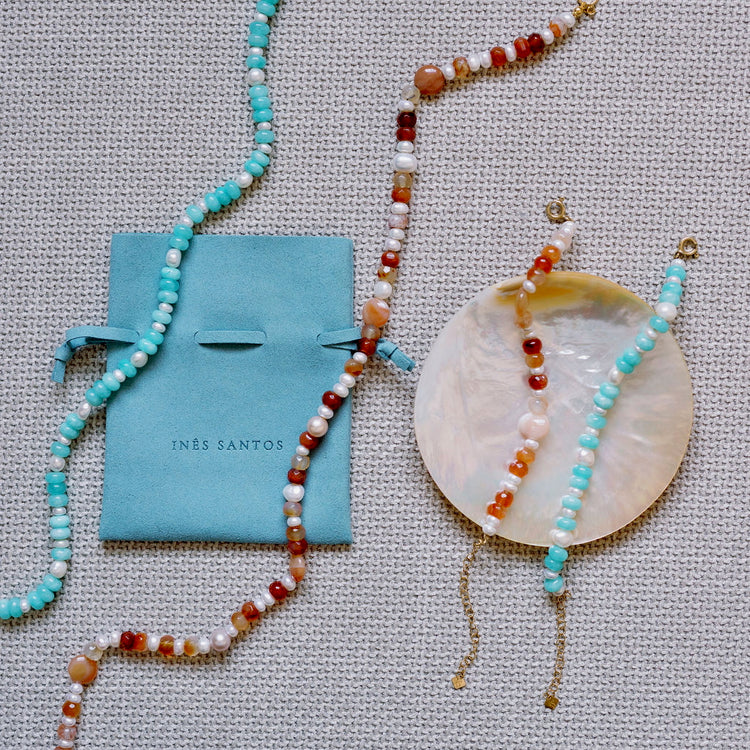 Beaded necklace and bracelet with an Inês Santos pouch on a textured surface