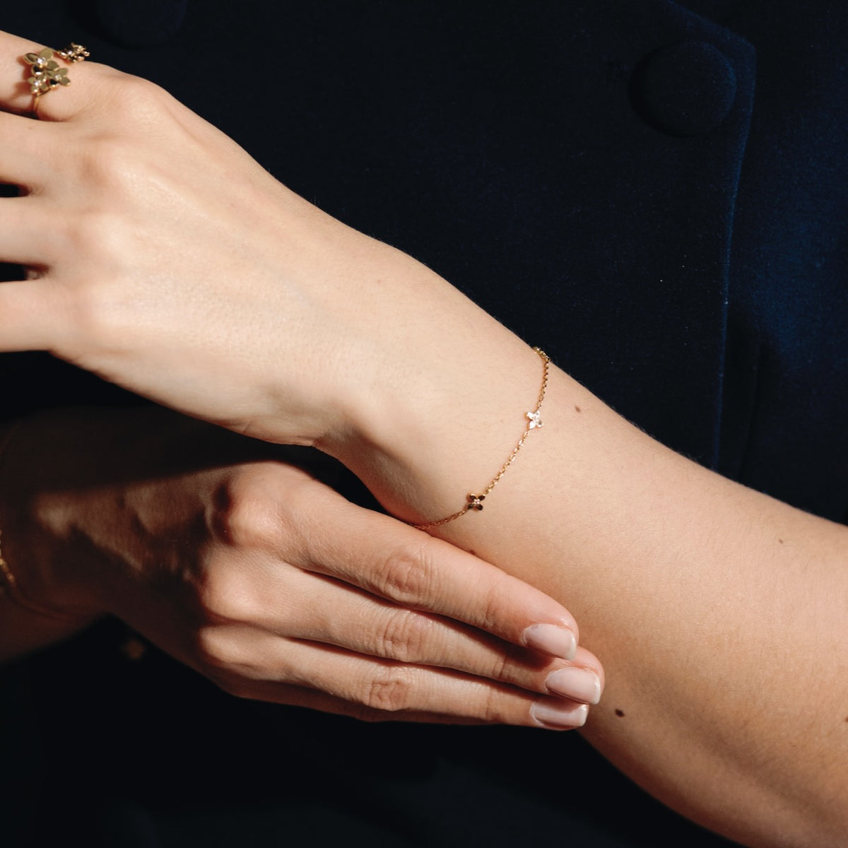 Close-up of a person's wrist wearing a delicate gold bracelet with a dark background.
