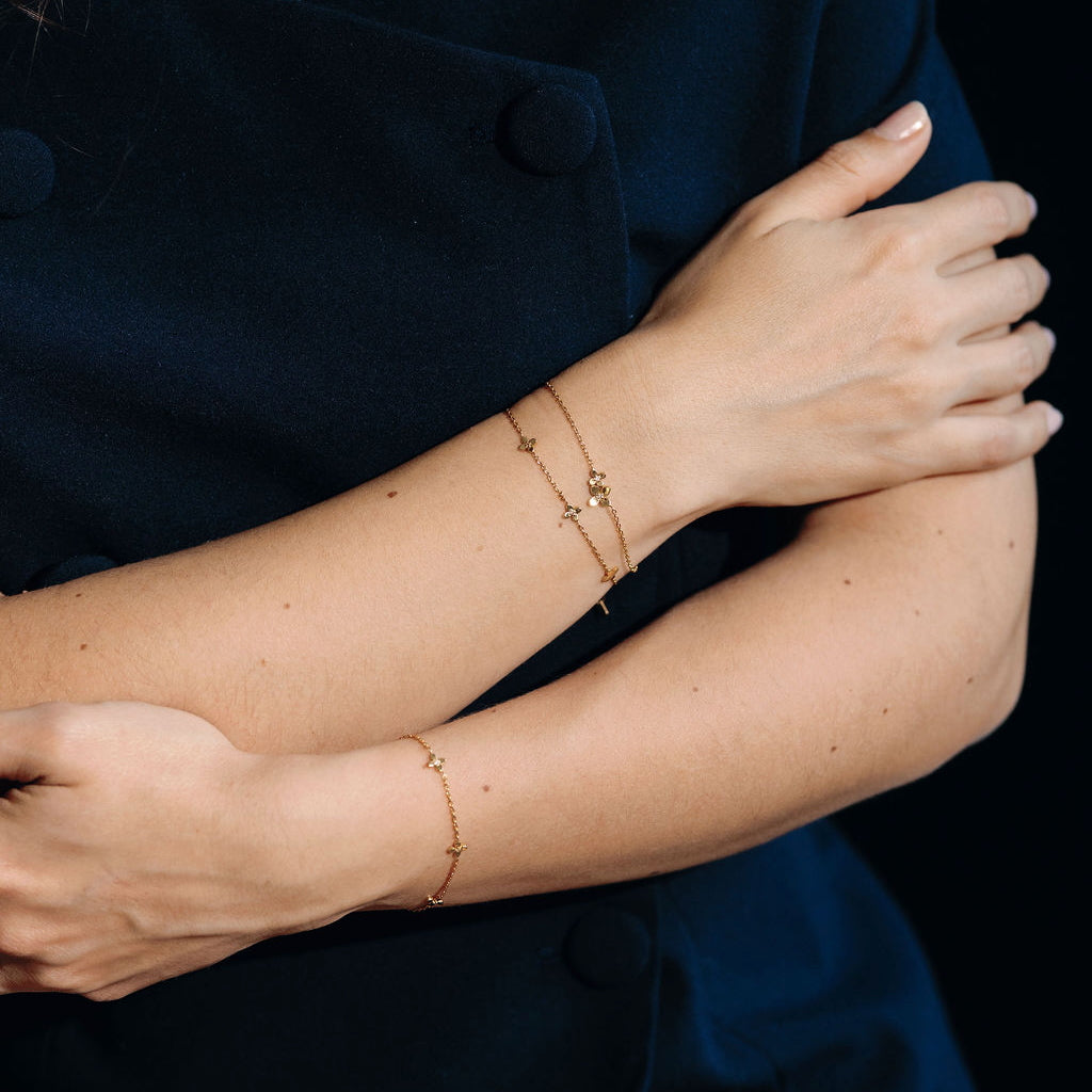 Close-up of a person wearing two gold bracelets on a dark background